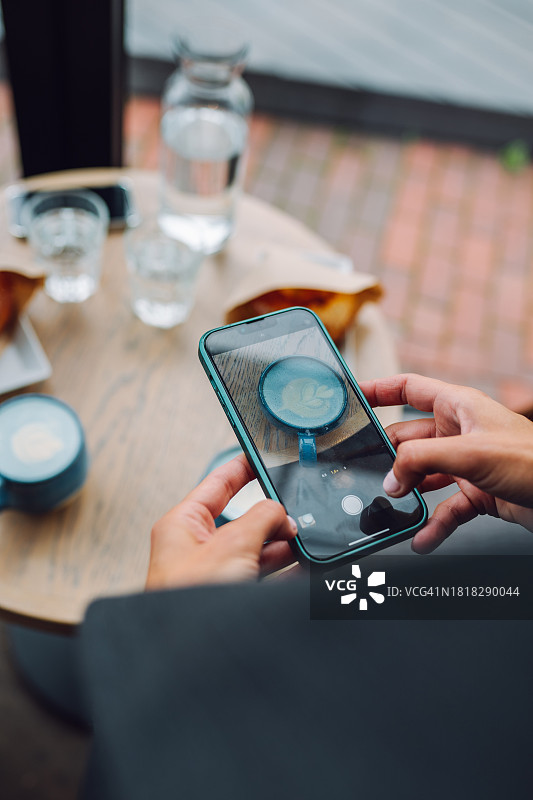 女子用智能手机在咖啡馆拍摄食物和饮料图片素材