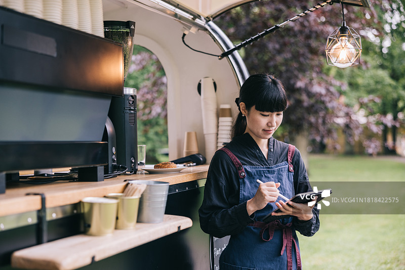 在咖啡车附近使用平板电脑的日本咖啡师图片素材