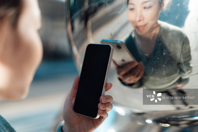 女性手持智能手机特写（反射金属背景）图片素材