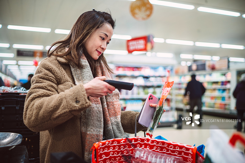 年轻女子在超市购物时使用手持条形码扫描器图片素材