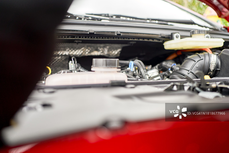 车库内汽车发动机正面视图，一人正在检查图片素材