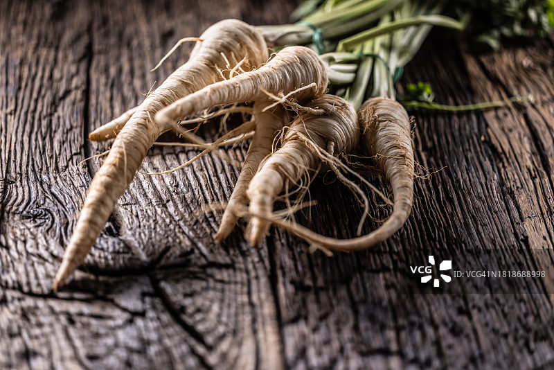 木板上的欧洲防风草根与欧芹叶特写图片素材