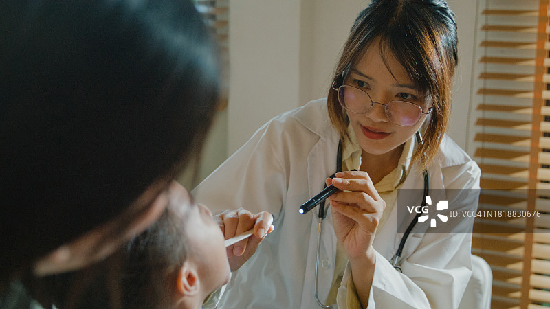 女医生在家中检查生病发高烧女孩的口腔和喉咙特写，生病女孩和妈妈在一起，关注医疗状况和家庭健康图片素材