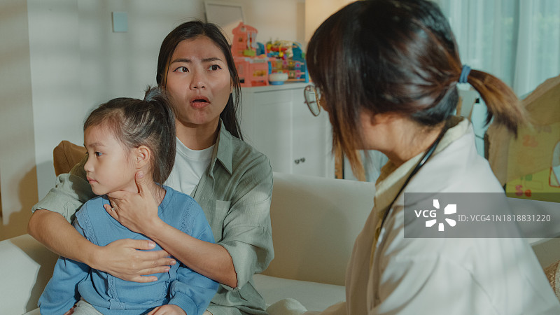 女医生在家中为发烧生病的女孩检查并提供建议，关注患病女孩与母亲的家庭健康图片素材