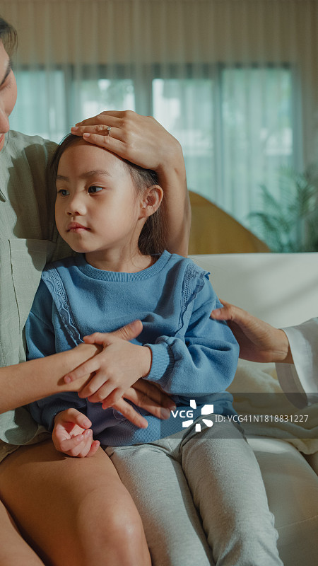 竖版女医生在家检查生病发烧小女孩皮肤。图片素材