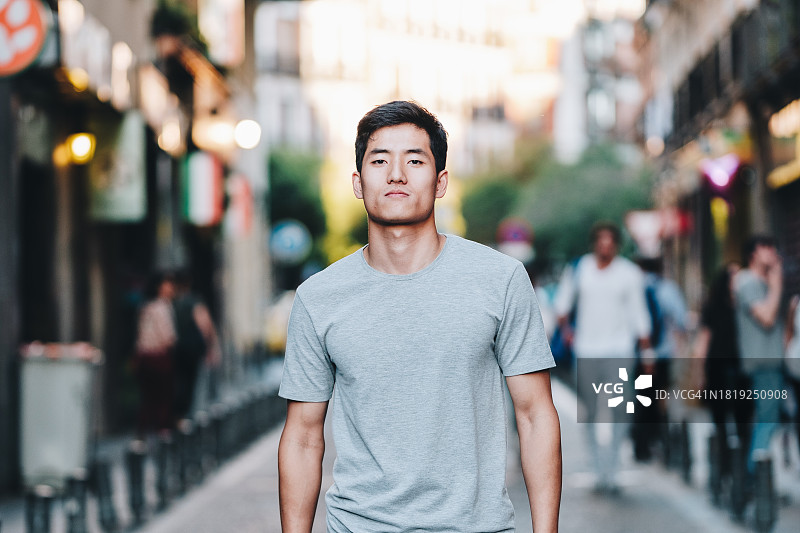 自信的年轻亚洲男子站在城市街道上图片素材