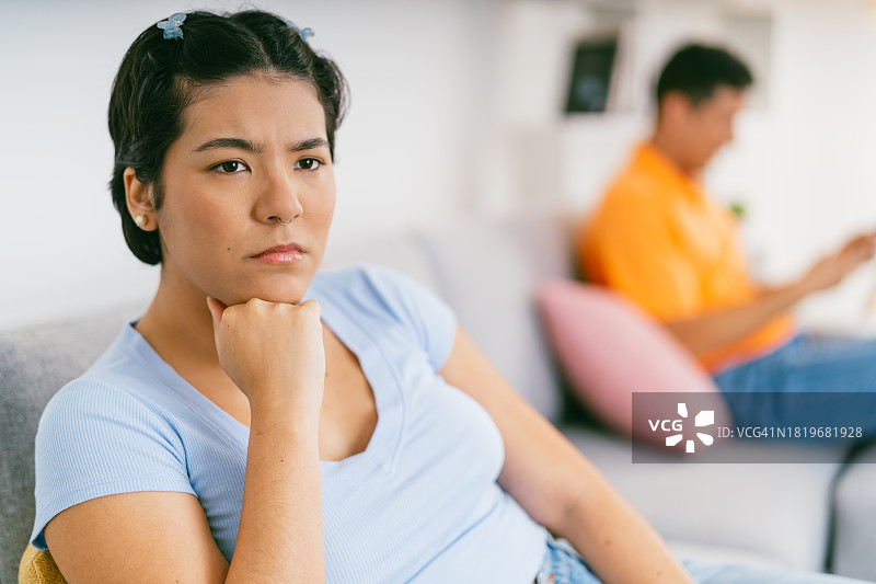 年轻女子对坐在沙发上的伴侣感到恼火图片素材