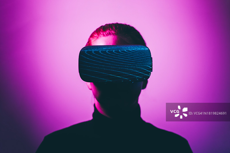 在霓虹灯中佩戴VR头显的年轻女人图片素材