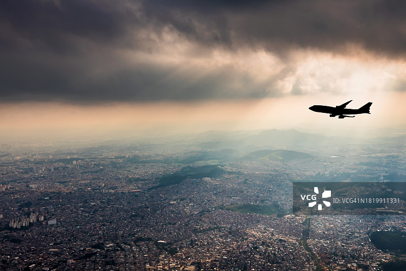 戏剧性天空下的都市上空的飞机图片素材