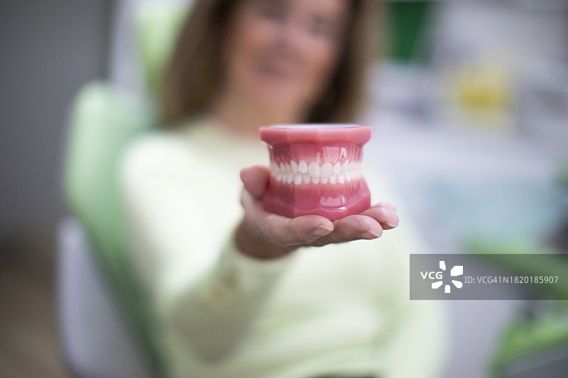 病人在牙科诊所手持隐形牙齿正畸模型图片素材