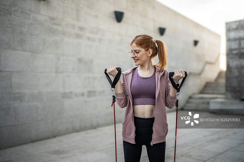 运动型女人在户外用阻力带锻炼图片素材