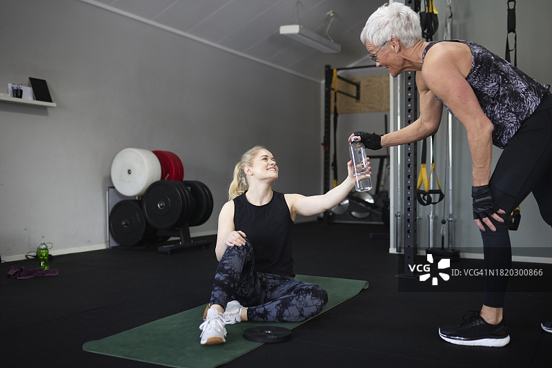 快乐的女人在健身俱乐部拿着水瓶图片素材