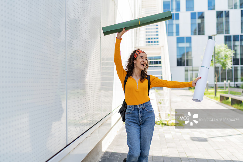 在大学外拿着蓝图的年轻女子肖像图片素材