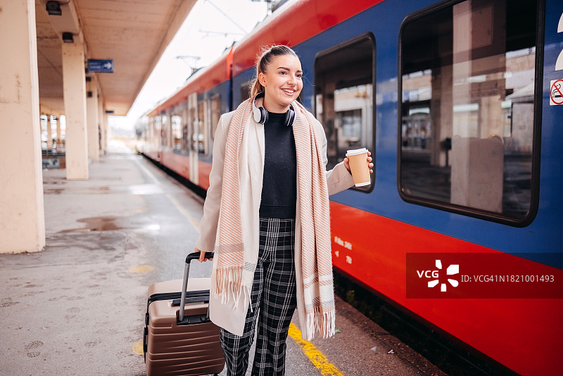 在火车站等候交通工具并拿着咖啡杯的年轻女商人图片素材