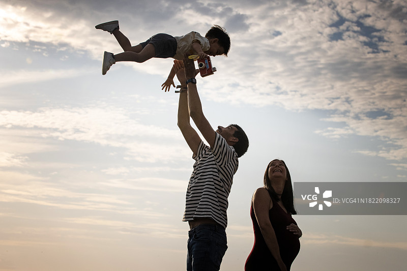 幸福夫妇与儿子玩耍的剪影：背光效果图片素材