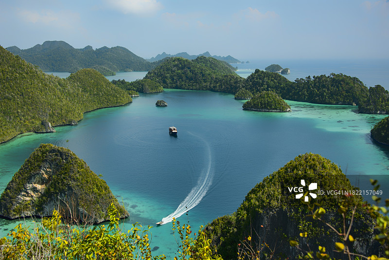 在印度尼西亚西巴布亚拉贾安帕群岛瓦亚格岛，快艇驶过热带泻湖中的游览船图片素材