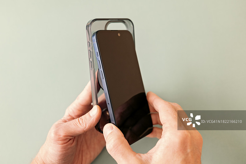 手将硅胶手机壳套在智能手机背面图片素材