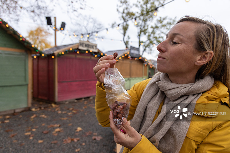 在冬季市场吃时令食品的无忧无虑的女人图片素材