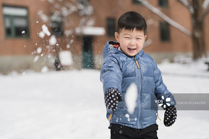 冬季滑梯冒险：男孩在城市雪地里玩耍图片素材