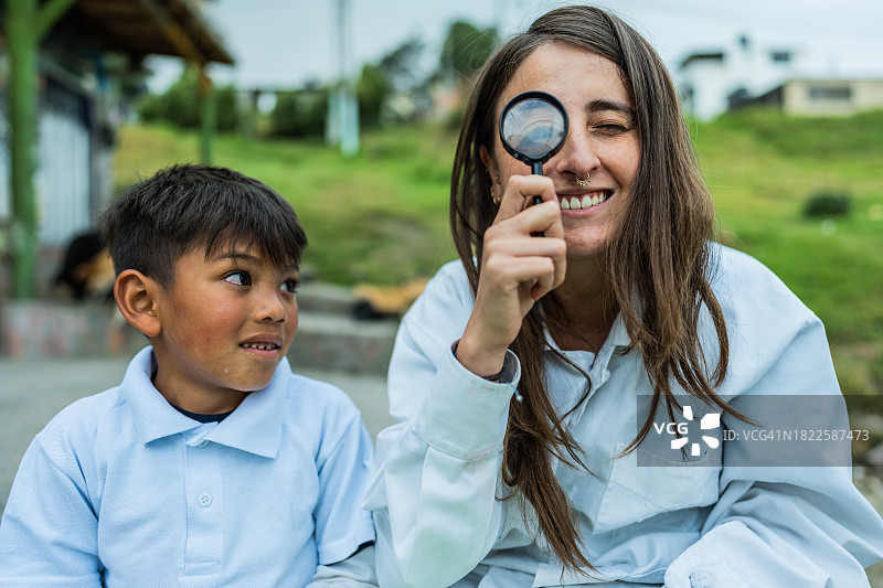 儿童看老师在户外使用放大镜图片素材