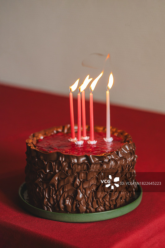 生日巧克力蛋糕，配有绿色盘子和红色桌布上的蜡烛图片素材