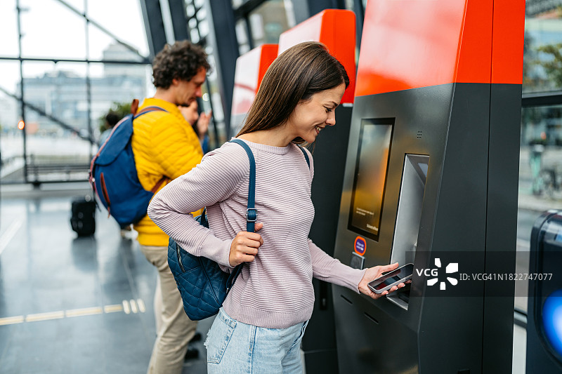 年轻女子在马尔默火车站用手机购买火车票图片素材