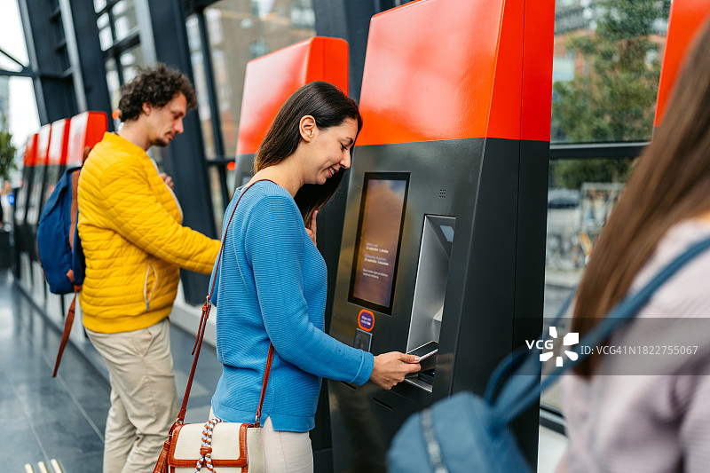 年轻女子在马尔默火车站用手机购买火车票图片素材