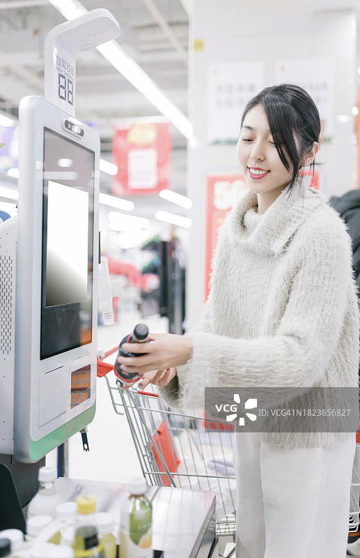 年轻的亚洲人在超市使用自助结账设备购物图片素材