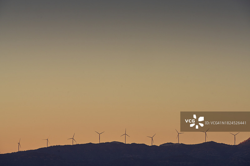 日落时分地平线上的风力发电场图片素材