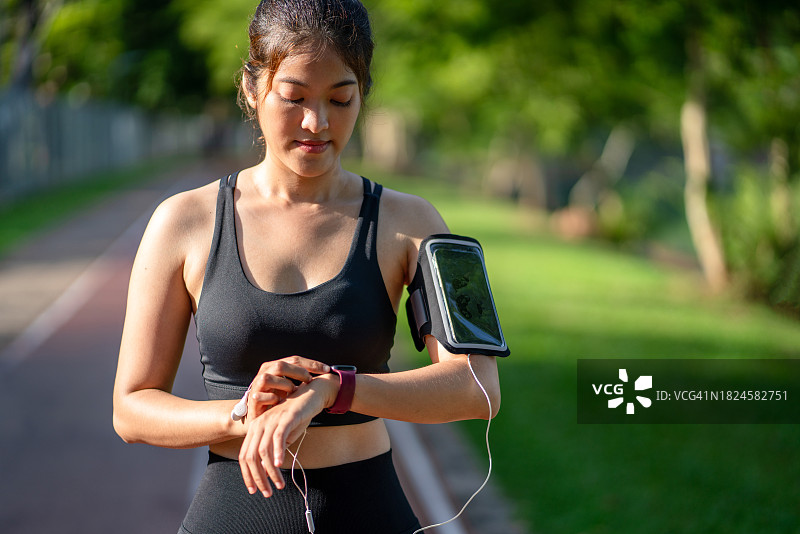 城市户外跑步的年轻女性与智能手表图片素材