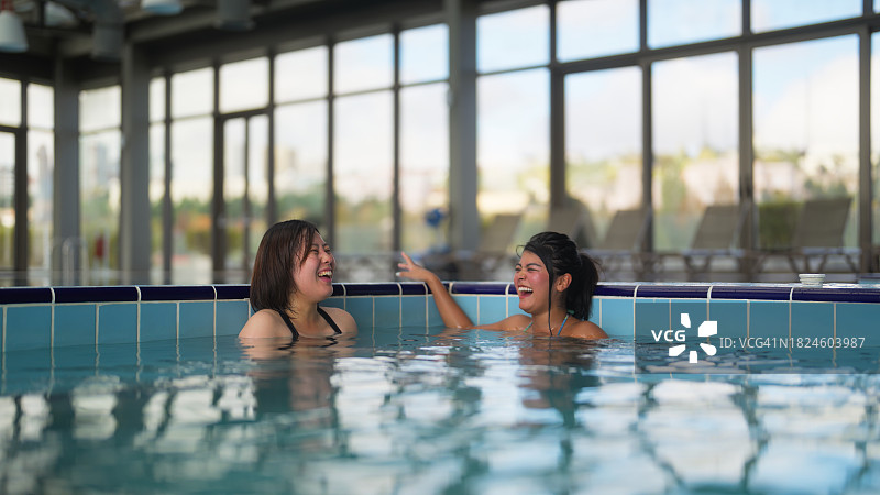 两个不同种族的女性游客在漩涡浴缸里放松身心，愉快地交谈图片素材