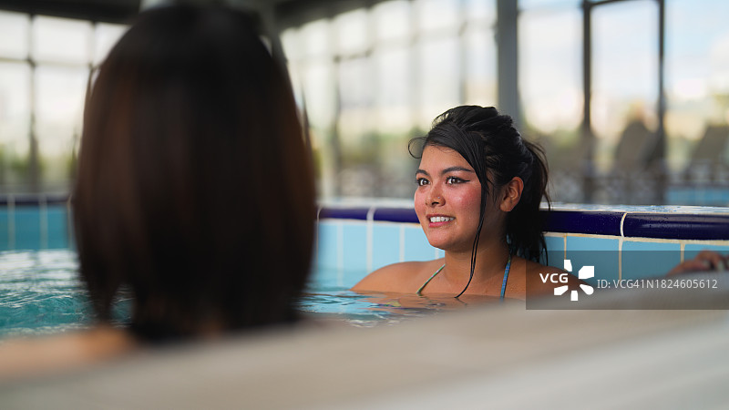 两个不同种族的女性游客在漩涡浴缸里放松身心，愉快地交谈图片素材