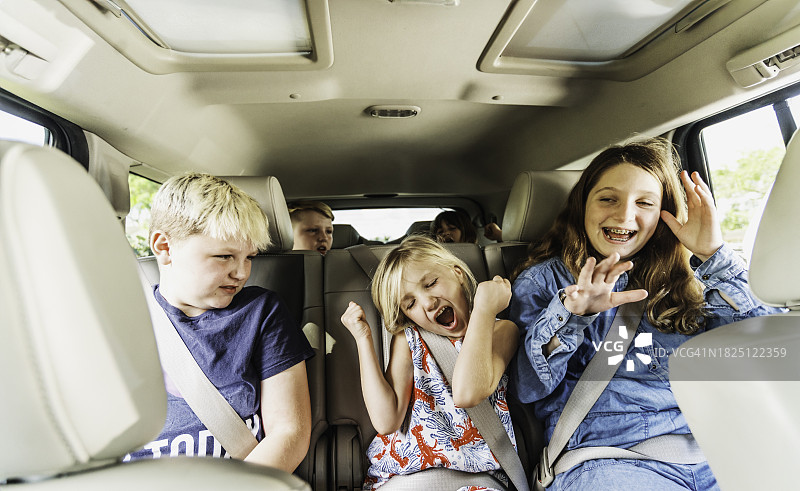 在汽车后座唱歌跳舞的快乐儿童图片素材