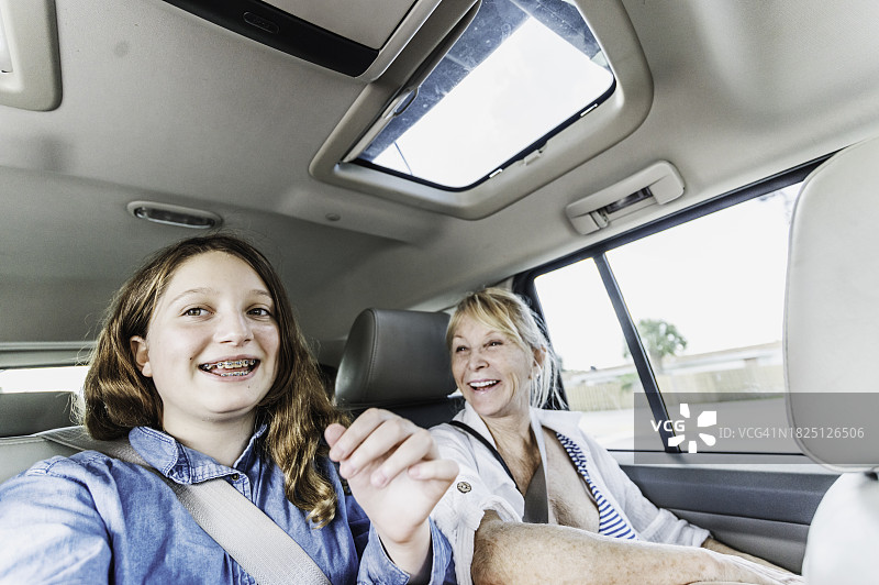 年长的妇女与年轻的少女在汽车后座，家庭旅行图片素材