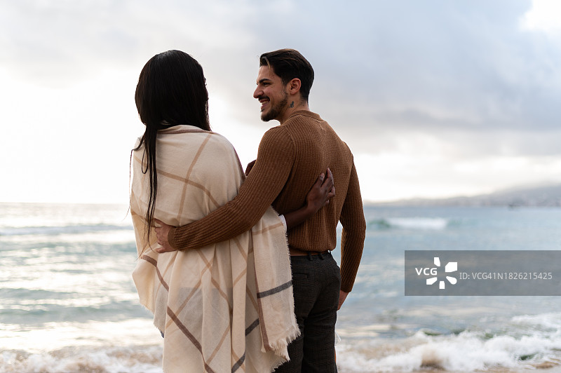 多民族情侣在海滩上面朝大海拥抱图片素材