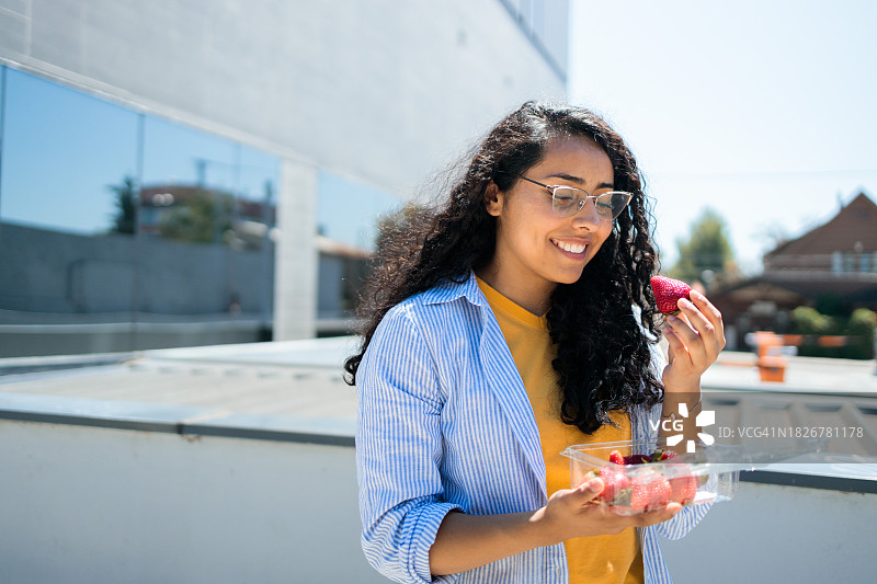 年轻拉丁裔女人办公室外吃草莓图片素材