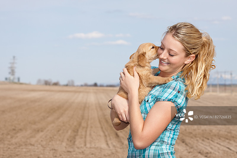 快乐的年轻女子抱着顽皮的小狗图片素材
