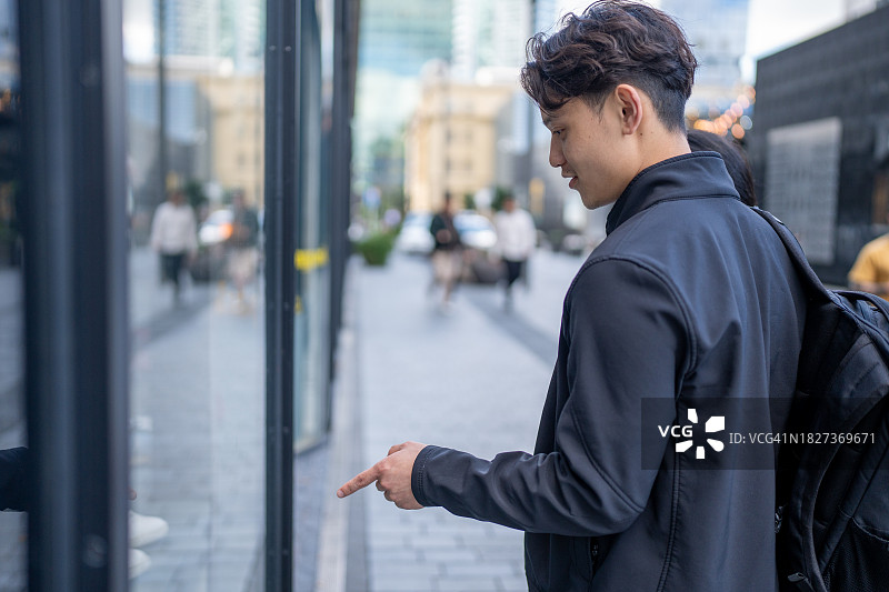 年轻的亚洲男人指向商店橱窗图片素材