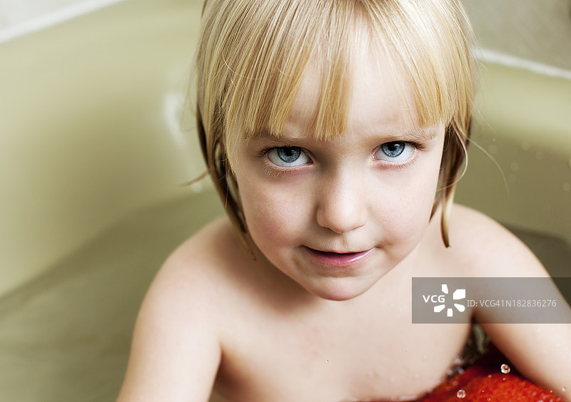 正在洗澡的漂亮金发幼儿抬头，表情严肃图片素材