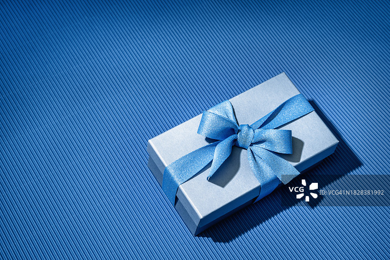 蓝色渐变背景上的蓝色蝴蝶结礼品盒图片素材