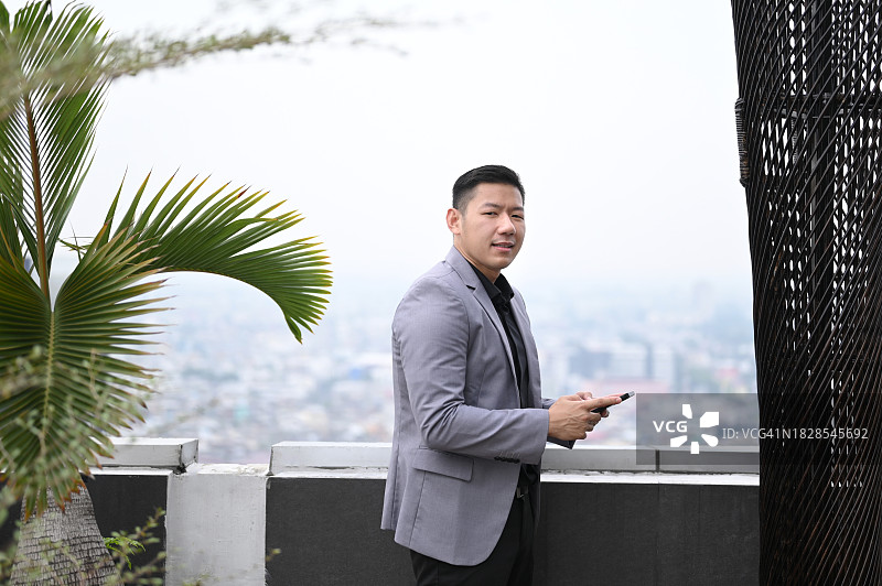 在屋顶上使用手机的商人图片素材