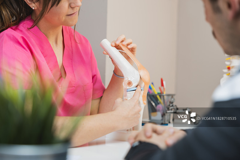 专业医生向患者演示膝关节功能模型图片素材