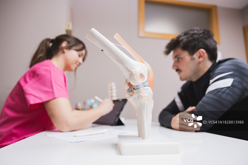 医生用平板电脑向患者展示膝盖模型图片素材