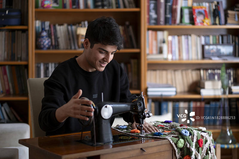 年轻男人在家用缝纫机修理二手产品图片素材