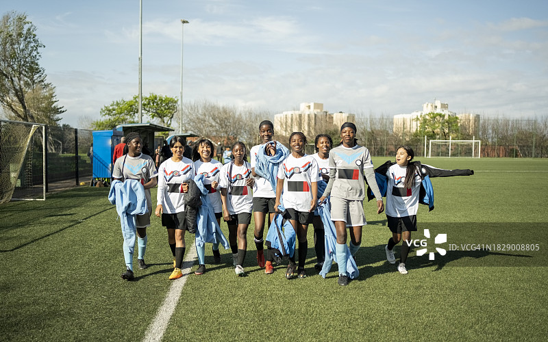 年轻女足球运动员在运动场训练后一起散步图片素材