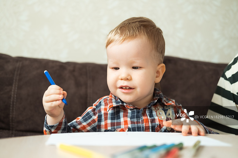 小男孩在桌旁用彩色铅笔画画图片素材
