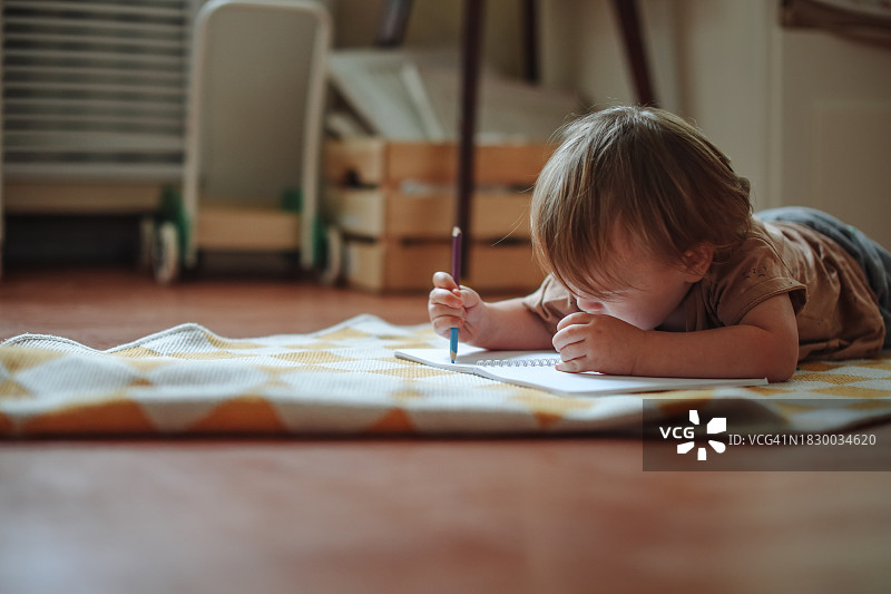 创意瞬间：幼儿在地板上用铅笔素描，留白图片素材