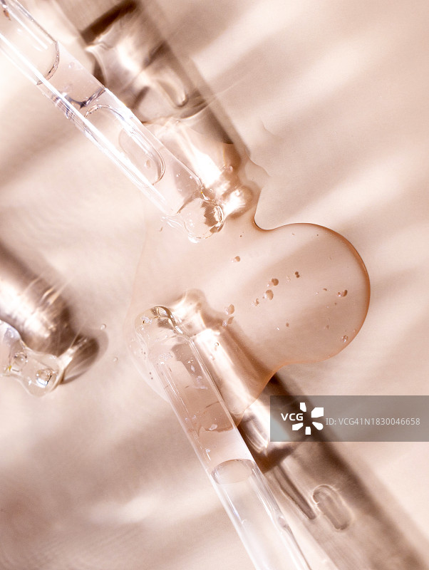 米色背景上的透明精华液玻璃滴管图片素材