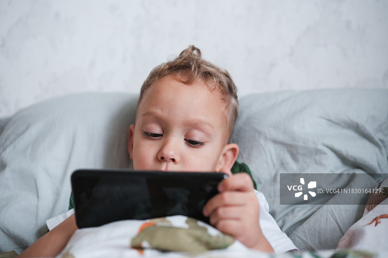 在家玩手机游戏的小男孩，儿童和数码设备图片素材