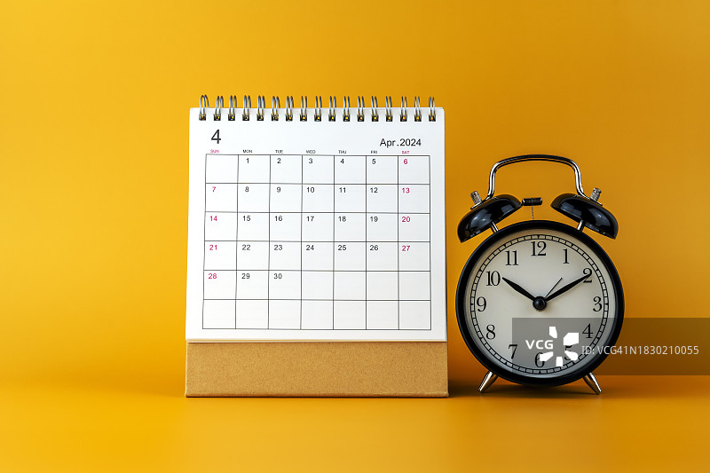 2024年4月日历和黄色背景上的闹钟图片素材